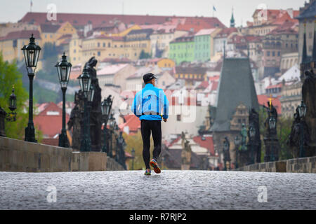 Uomo che gestisce la città, vista posteriore di un uomo di mezza età che corre da solo sul Ponte Carlo a Praga la mattina presto, Praga, Repubblica Ceca. Foto Stock