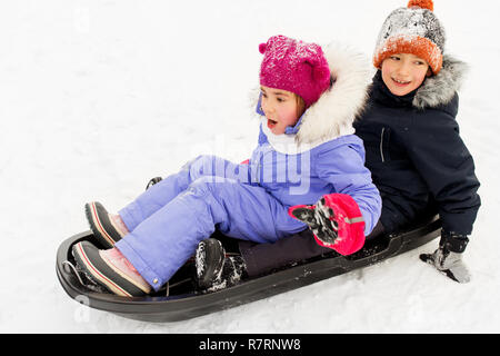 Bambini piccoli scorrevole sulla slitta giù per la collina in inverno Foto Stock