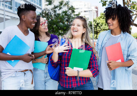 Ridendo bionda studentessa con gruppo di studenti internternational outdoor in città Foto Stock