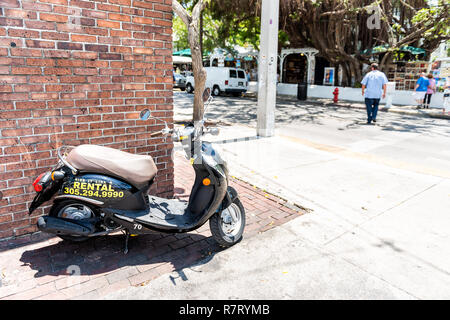 Key West, Stati Uniti d'America - 1 Maggio 2018: Scooter moto parcheggiata su Duval Street in Florida City travel, giornata di sole sulla strada, affitto affitto segno con numero di telefono Foto Stock