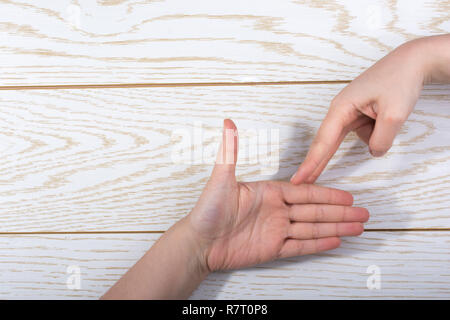 Mani rendendo Rock, Paper, Scissors gesto su uno sfondo di legno Foto Stock