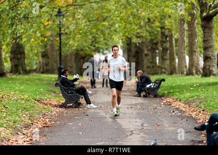 London, Regno Unito - 12 Settembre 2018: uomo correre in vicolo percorso nel parco verde in Westminster, vista orizzontale durante il piovoso verde bagnato estate, autunno in Unite Foto Stock