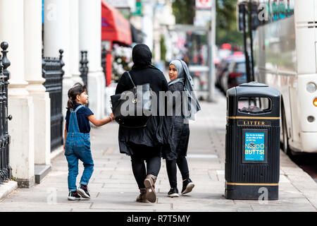 London, Regno Unito - 16 Settembre 2018: il popolo arabo e musulmano a piedi di famiglia con la donna in hijab abbigliamento sul marciapiede street con i bambini in Kensington Foto Stock