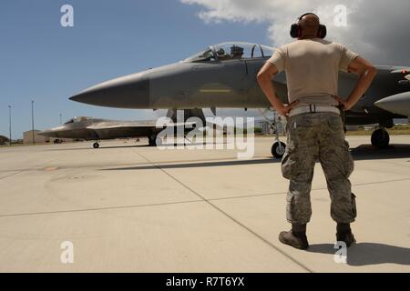 Stati Uniti Air Force Staff Sgt. Raymon Figuero, un capo equipaggio con la 144Manutenzione aeromobili squadrone, è pronta a lanciare un F-15C Eagle come un F-22 Raptor, dalle Hawaii Air National Guard, taxi da durante Sentry Aloha 17-03, 29 marzo 2017. Il multi-stato excercise fornisce realistico aria-aria disimilar fighter training. L'esercizio in corso è ospitato dalla 154ala, Hawaii Air National Guard. ( Foto Stock