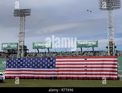 Avieri salute durante la riproduzione di un inno nazionale al Fenway Park di Boston Red Sox in apertura di giornata festeggiamenti Aprile 3, mentre F-15s dal 104th Fighter Wing da Barnes Air National Guard Base, Massachusetts, eseguire un sorvolare. Hanscom AFB ha una lunga tradizione di partenariato comunitario con i Red Sox organizzazione. Foto Stock