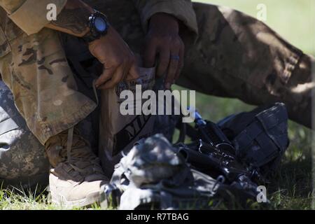 Stati Uniti Army Ranger si prende una pausa per reintegrare le sostanze nutritive in tra gli eventi durante la migliore concorrenza Ranger 2017 a Fort Benning, Ga., Aprile 7, 2017. La trentaquattresima edizione annuale di David E. Grange Junior Ranger migliore concorrenza 2017 è un evento di tre giorni consistente di sfide per testare concorrente del fisico, mentale e capacità tecniche. Foto Stock