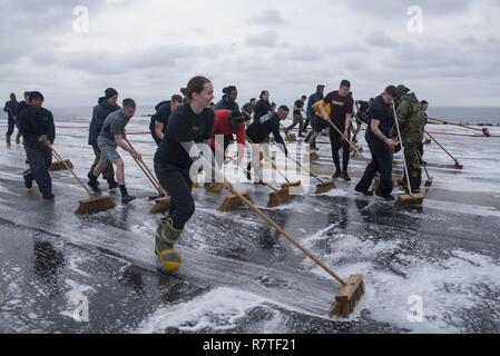 Mare del Giappone (9 aprile 2017) Reparto aria marinai scrub il ponte di volo dell'assalto anfibio nave USS Bonhomme Richard (LHD 6) a seguito di una soluzione acquosa di formazione di film (schiuma AFFF) contromisura lavaggio. AFFF è una miscela di acqua e altamente concentrato detergente usato sul ponte di volo e hangar bay a soffocare gli incendi. Bonhomme Richard, ammiraglia del Bonhomme Richard anfibio gruppo pronto è su una pattuglia, operando in Indo-Asia-regione del Pacifico per migliorare la prontezza combattimento e la postura in avanti come una pronta risposta in vigore per qualsiasi tipo di emergenza. Foto Stock