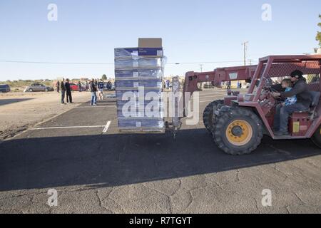 Andrew Hecker e il suo 2-anno-vecchio figlio Ezechiele lo scarico di pallet di cibo in preparazione per impilare nel parcheggio della Betania fraternità cristiana chiesa sulla strada Amory Marzo 24. Hecker dona il suo tempo alla dispensa alimentare organizzato dai gruppi caritativi benedizioni e militari di benedizioni. Il carrello elevatore a forche viene donata da Silver Valley propano, Hecker del datore di lavoro. Foto Stock