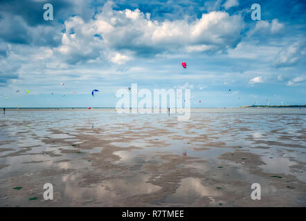 Persone sportive e kite surf sulla spiaggia con le nuvole nel cielo su una spiaggia in Olanda Foto Stock