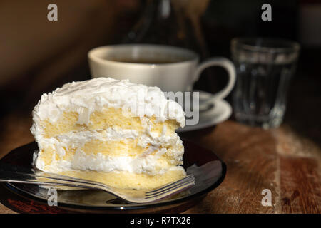 Close up pezzo di chiffon cocco torta sul tavolo di legno con il caldo sole di mattina la luce Foto Stock