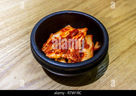 Kimchi coreano in una piccola ciotola nero con rosso di salsa al peperoncino Foto Stock