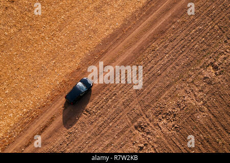 Vista aerea del nero auto sulla strada sterrata attraverso la campagna, vista superiore durante la guida del veicolo da fuco pov Foto Stock