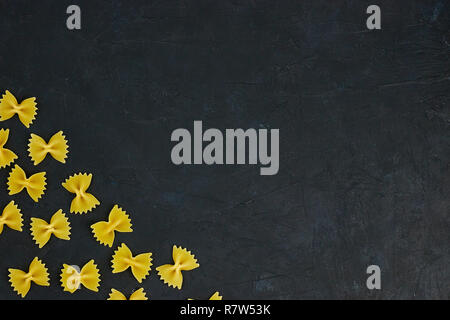 Paste alimentari non cotte legato con una corda su calcestruzzo su sfondo nero. copia spazio. vista dall'alto. Foto Stock