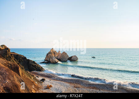 Pomeriggio Vista del paesaggio marino attorno a Petra tou Romiou, in Paphos, Cipro, come una barca da pesca passa da. È considerato essere Aphrodite il luogo di nascita Foto Stock