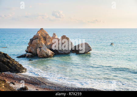 Pomeriggio Vista del paesaggio marino attorno a Petra tou Romiou, in Paphos, Cipro, come una barca da pesca passa da. È considerato essere Aphrodite il luogo di nascita Foto Stock