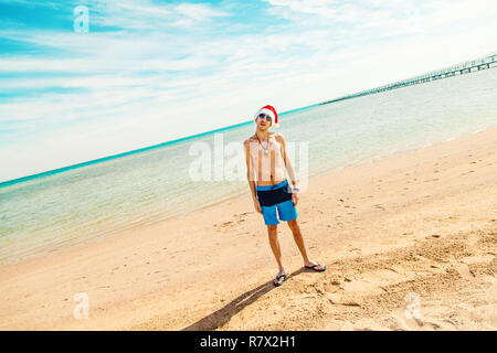 Un uomo in un cappello da Babbo Natale sulla spiaggia. Messa a fuoco selettiva. vacanze. Foto Stock