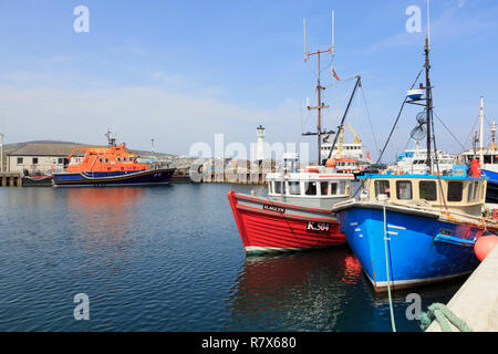 Barche da pesca ormeggiate nel porto interno con una scialuppa di salvataggio al di là. Kirkwall, Orkney continentale, Scozia, Regno Unito, Gran Bretagna Foto Stock