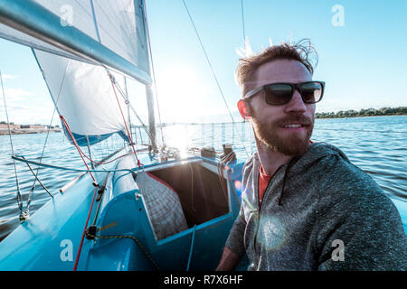 L'uomo comanda la barca con il timone a poppa durante la navigazione sul fiume al giorno di estate Foto Stock
