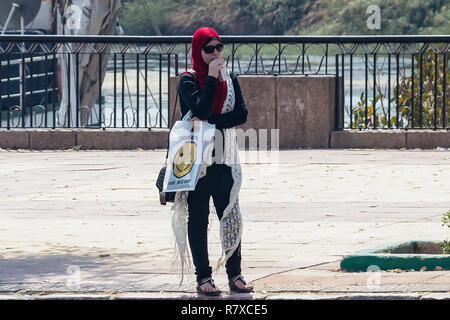 Aswan, Egitto - 11 Settembre 2018: Arabian donna con hijab bere un succo di frutta in strada Foto Stock