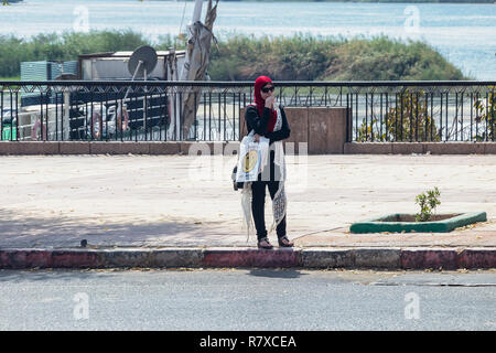 Aswan, Egitto - 11 Settembre 2018: Arabian donna con hijab bere un succo di frutta in strada Foto Stock