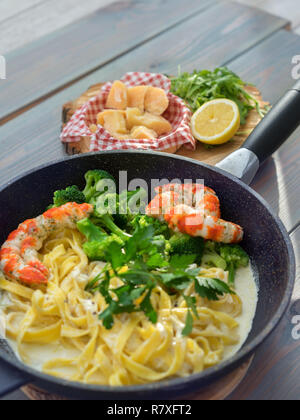 Tutta la granella di pasta con gamberi e formaggio sulla tavola di legno, vista dall'alto Foto Stock