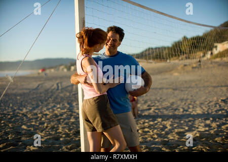 Mid-adulto giovane giocando a pallavolo sulla spiaggia. Foto Stock