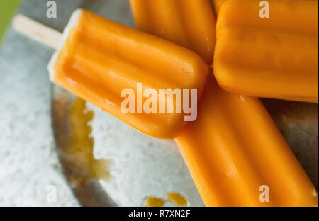 Varie arancio e vaniglia creamsicles su una lastra di acciaio galvanizzato e un verde lime dello sfondo. Foto Stock