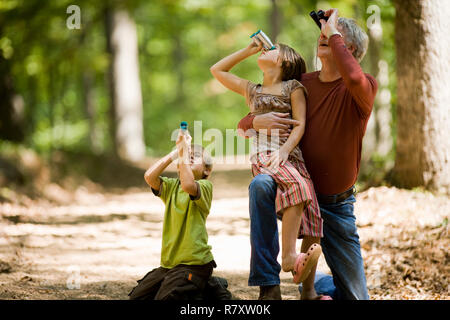 Famiglia guardando attraverso il binocolo nel bosco Foto Stock