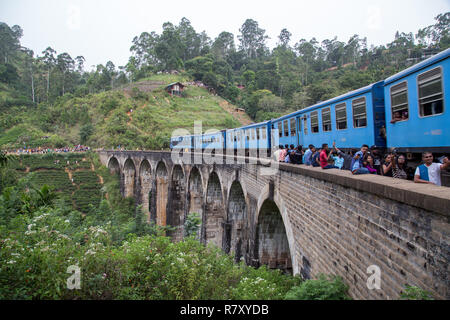 Demodara, Sri Lanka - 5 Agosto 2018: le persone accanto a un treno blu attraversando il famoso nove ponte di Arco Foto Stock