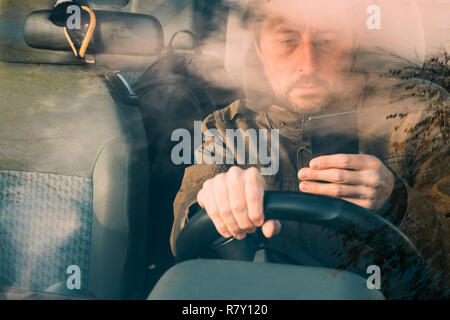 Vista anteriore dell uomo alla guida di auto e i messaggi di testo sul telefono cellulare che è pericoloso e comportamento incauto Foto Stock