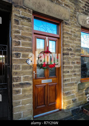 A piena altezza casa porta anteriore con la ghirlanda di Natale su una pietra costruito cottage in Sheffield South Yorkshire, Inghilterra Foto Stock