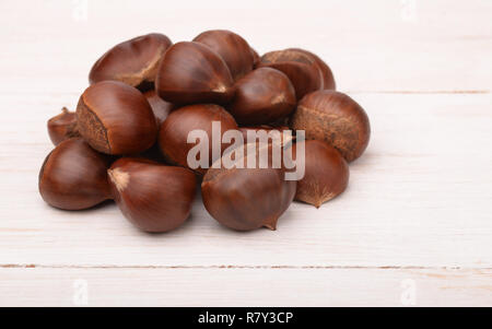 Pila di di castagne fresche in bianco sullo sfondo di legno Foto Stock