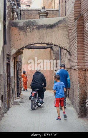 05-03-15, Marrakech, Marocco. Scena di strada nel souk della medina. Una donna su uno scooter tesse passato due pedoni. Foto: © Simon Grosset Foto Stock
