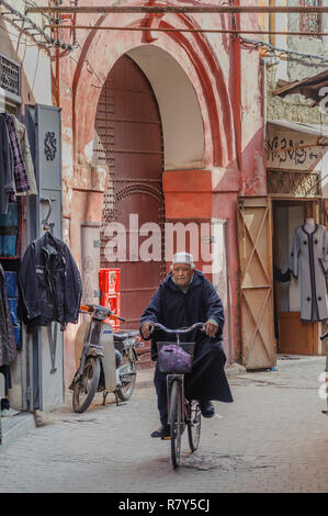 05-03-15, Marrakech, Marocco. Scena di strada nel souk della medina, nella vecchia, antico, parte della citta'. Un uomo che cavalca una bicicletta giù per una strada, tutti Foto Stock