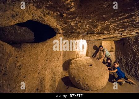 Turchia, Anatolia centrale, Nevşehir provincia, Cappadocia UNESCO World Heritage Site, Famiglia scoperta della città sotterranea di Kaymakli, costruita su 8 livelli che poteva accogliere 5000 persone, qui una vecchia porta scorrevole giacente a terra Foto Stock