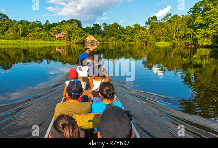 Trasporto in canoa lungo i fiumi del bacino del Rio delle Amazzoni all'interno del Parco Nazionale di Yasuni con un Lodge in stile architettonico tradizionale, Ecuador. Foto Stock