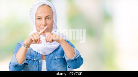 La mezza età araba orientale donna che indossa arabian hijab su sfondo isolato rifiuto espressione dita incrociate facendo segno negativo Foto Stock