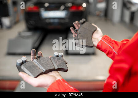 Meccanico automatico tenendo premuto di nuovo e usato pastiglie del freno all'auto di servizio, vista da vicino Foto Stock