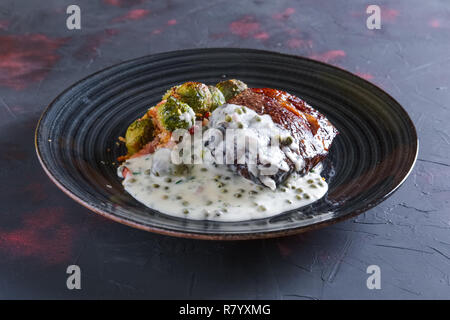 Bistecca di manzo fritto con cavolini di Bruxelles e cremosa salsa di piselli Foto Stock