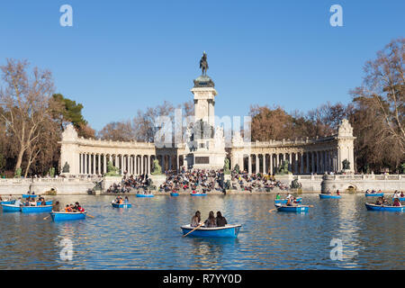 I turisti il canottaggio tradizionale blu barche sul lago nella città di Retiro park su una soleggiata giornata invernale a Madrid, Spagna. Foto Stock