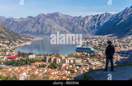 Turistico con un cappello ammirando il panorama mozzafiato della Baia di Kotor in Montenegro come visto dalla strada al parco nazionale di Lovcen Foto Stock