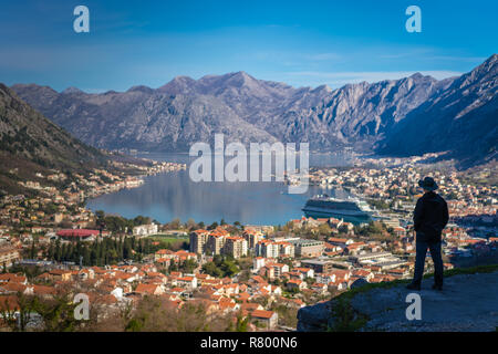 Turistico con un cappello ammirando il panorama mozzafiato della Baia di Kotor in Montenegro come visto dalla strada al parco nazionale di Lovcen Foto Stock