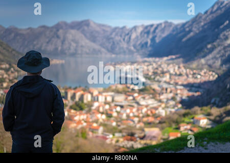 Turistico con un cappello ammirando il panorama mozzafiato della Baia di Kotor in Montenegro come visto dalla strada al parco nazionale di Lovcen Foto Stock