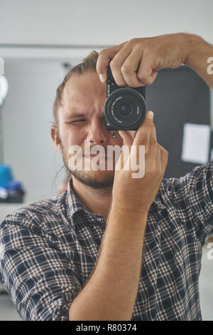 Fotografo guardando attraverso la telecamera al visualizzatore. Foto Stock