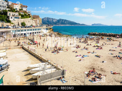 La gente a prendere il sole e nuotare sul profeta beach a Marsiglia, molto popolare di famiglia spiaggia situato sulla Corniche Kennedy, su una soleggiata giornata di primavera. Foto Stock