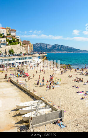 La gente a prendere il sole e nuotare sul profeta beach a Marsiglia, molto popolare di famiglia spiaggia situato sulla Corniche Kennedy, su una soleggiata giornata di primavera. Foto Stock