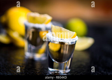Tradizionale messicano Tequila con limone, sale e il cubo di ghiaccio sulla pietra scura tabella tabella Foto Stock