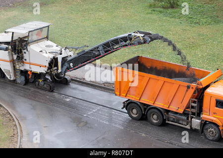 Fresatrice stradale rimuove il vecchio asfalto e carichi di asfalto fresato in camion. Strada del processo di riparazione. Elevato angolo di visione Foto Stock