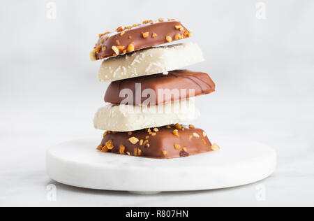 Il lusso di cioccolato belga e di cocco e selezione dei cookie sul marmo montagne russe e tavolo da cucina dello sfondo. Foto Stock