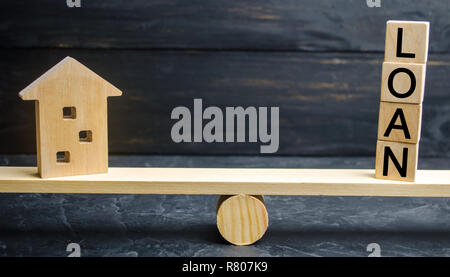 Miniatura casa in legno e la scritta " prestito " sono sulle scale. Acquisto di una casa in debito. Famiglia gli investimenti in proprietà immobiliari e la gestione del rischio conc Foto Stock